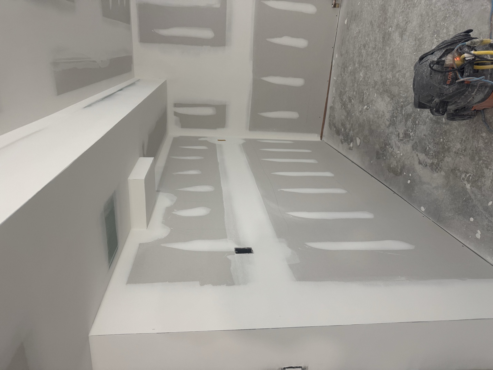 Basement room with drywall joints taped and first compound coat applied